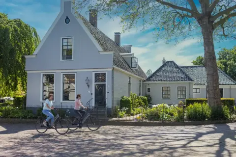 Cyclistes longeant des maisons traditionnelles &agrave; Broek in Waterland